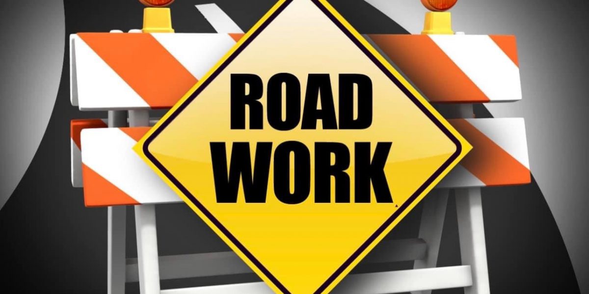 Barricade with orange lights and a yellow diamond sign reading "ROAD WORK."